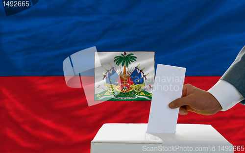 Image of man voting on elections in haiti in front of flag