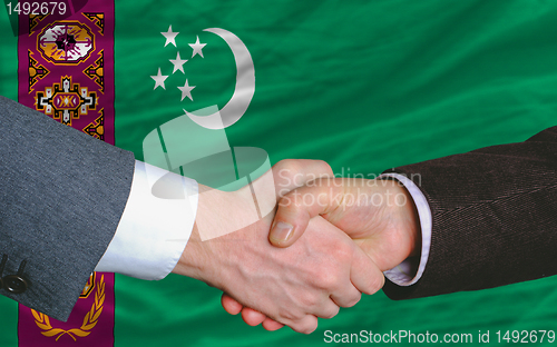 Image of businessmen handshake after good deal in front of turkmenistan f
