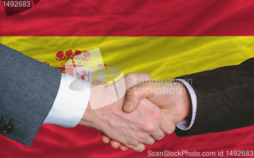Image of businessmen handshake after good deal in front of spain flag