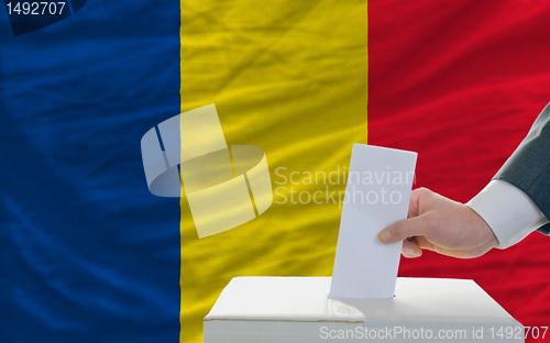 Image of man voting on elections in romania in front of flag