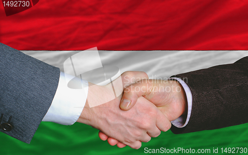 Image of businessmen handshake after good deal in front of hungary flag