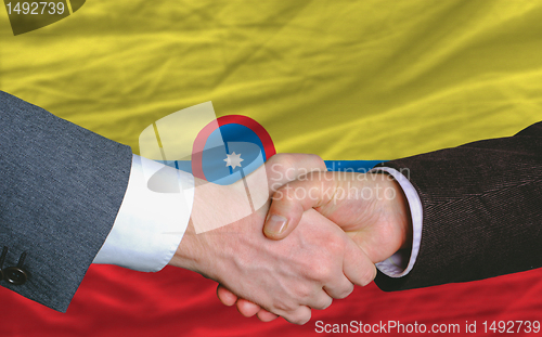 Image of businessmen handshakeafter good deal in front of columbia flag