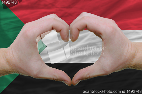 Image of Heart and love gesture showed by hands over flag of sudan backgr