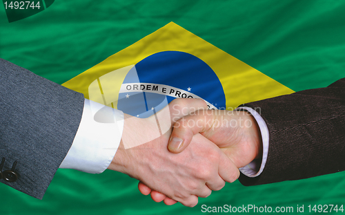 Image of businessmen handshake after good deal in front of brazil flag