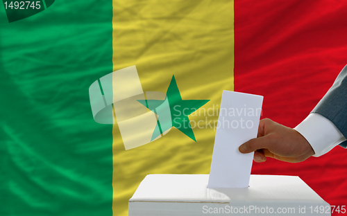 Image of man voting on elections in senegal in front of flag