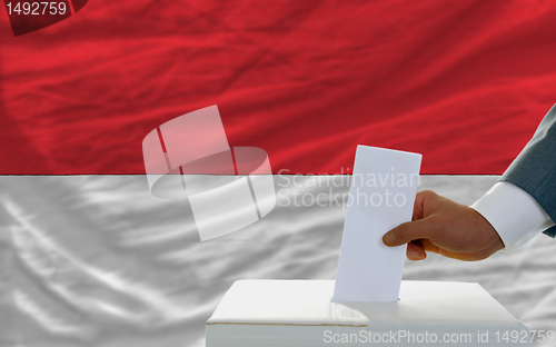 Image of man voting on elections in indonesia in front of flag