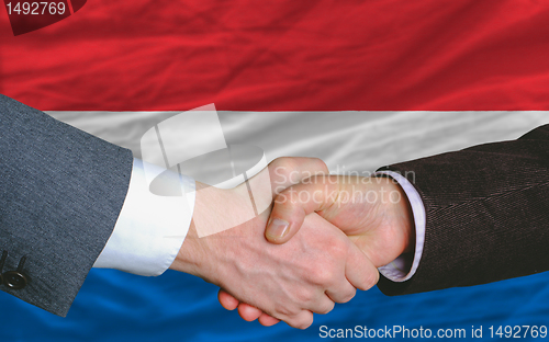 Image of businessmen handshake after good deal in front of netherlands fl