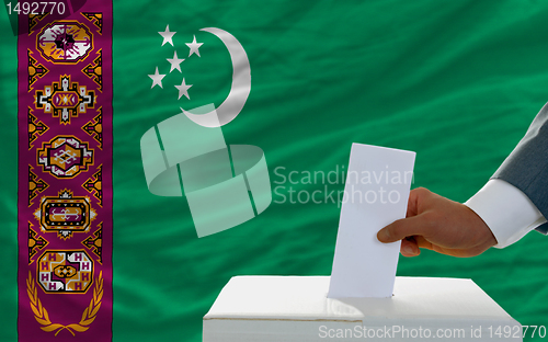 Image of man voting on elections in turkmenistan in front of flag