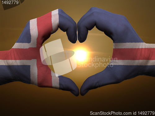 Image of Heart and love gesture by hands colored in iceland flag during b