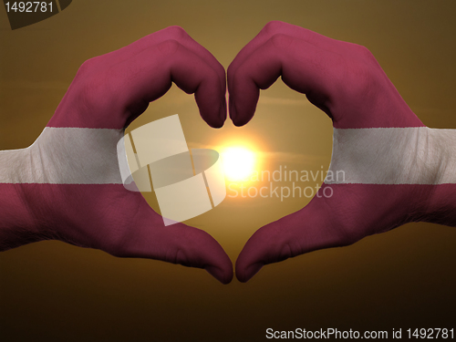 Image of Heart and love gesture by hands colored in latvia flag during be