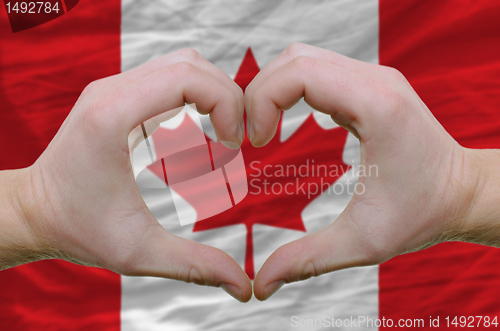 Image of Heart and love gesture showed by hands over flag of canada backg