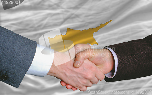 Image of businessmen handshake after good deal in front of cyprus flag