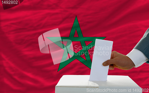 Image of man voting on elections in morocco in front of flag