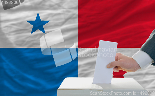 Image of man voting on elections in panama in front of flag