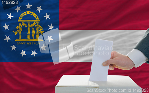 Image of man voting on elections in georgia in front of flag