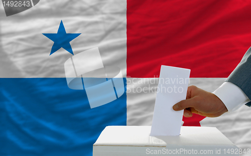 Image of man voting on elections in panama in front of flag