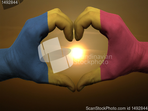 Image of Heart and love gesture by hands colored in romania flag during b