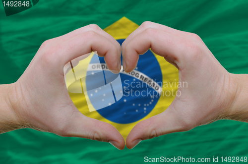 Image of Heart and love gesture showed by hands over flag of brazil backg