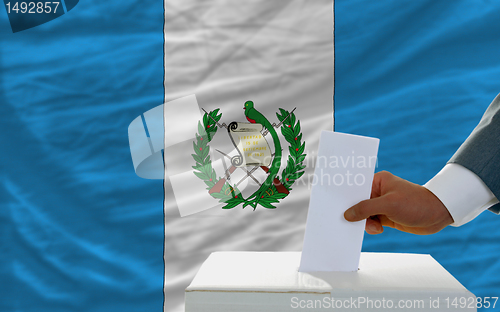 Image of man voting on elections in guatemala in front of flag