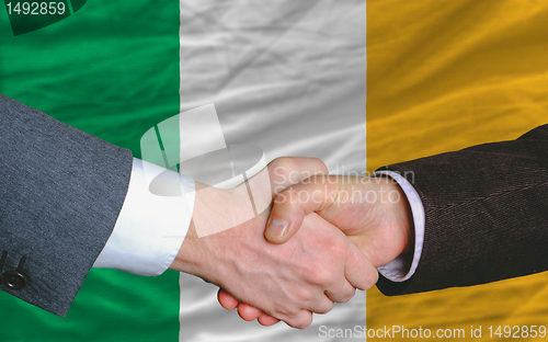 Image of businessmen handshake after good deal in front of ireland flag