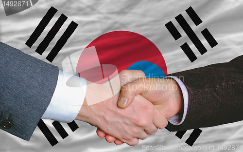 Image of businessmen handshake after good deal in front of south korea fl