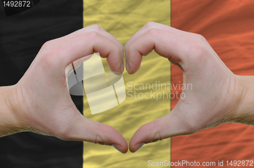 Image of Heart and love gesture showed by hands over flag of belgium back
