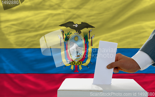 Image of man voting on elections in ecuador in front of flag