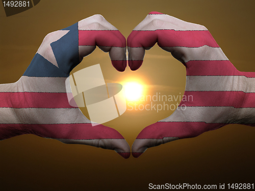 Image of Heart and love gesture by hands colored in liberia flag during b