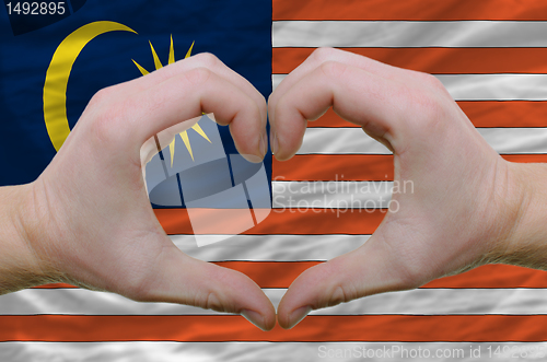 Image of Heart and love gesture showed by hands over flag of malaysia bac