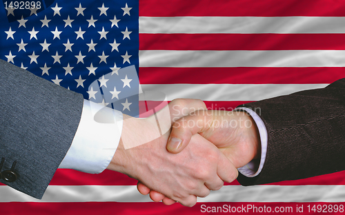 Image of businessmen handshake after good deal in front of america flag