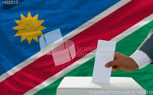 Image of man voting on elections in namibia in front of flag