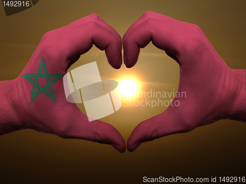 Image of Heart and love gesture by hands colored in morocco flag during b