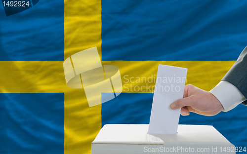 Image of man voting on elections in sweden in front of flag