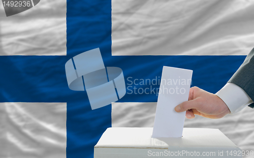 Image of man voting on elections in finland in front of flag