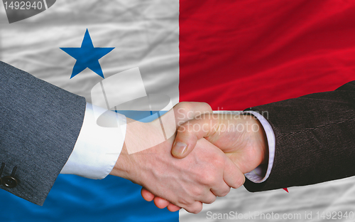 Image of businessmen handshake after good deal in front of panama flag