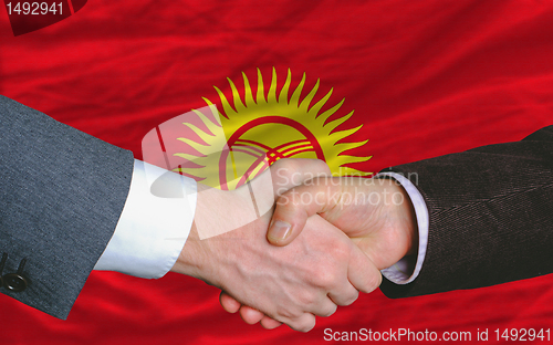 Image of businessmen handshake after good deal in front of kyrghyzstan fl