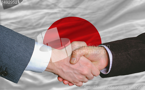 Image of businessmen handshake after good deal in front of japan flag