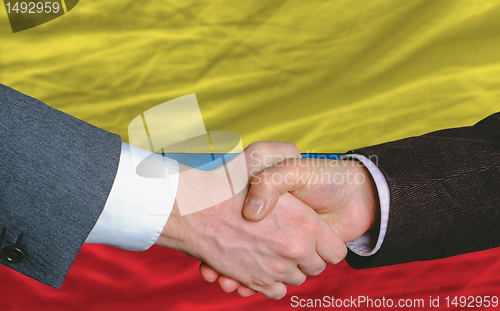 Image of businessmen handshakeafter good deal in front of columbia flag