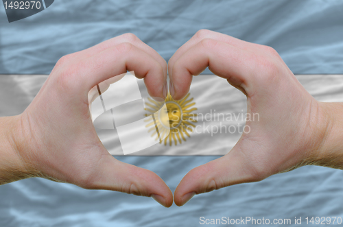 Image of Heart and love gesture showed by hands over flag of Argentina ba