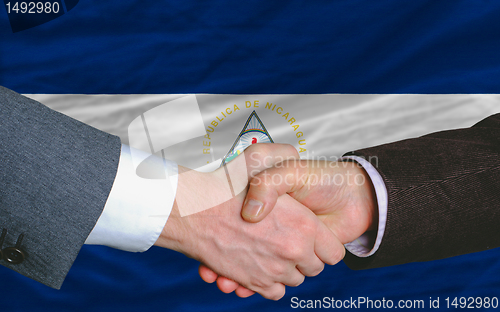 Image of businessmen handshake after good deal in front of nicaragua flag