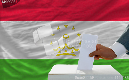 Image of man voting on elections in tajikistan in front of flag