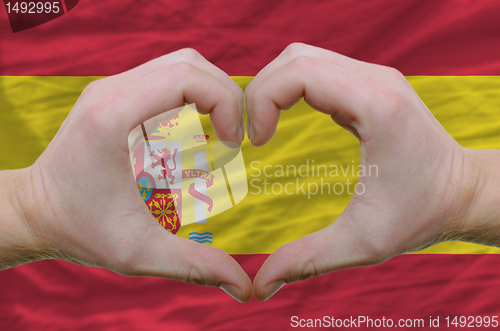 Image of Heart and love gesture showed by hands over flag of spain backgr