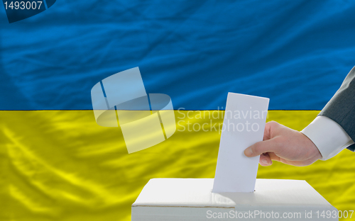Image of man voting on elections in ukraine in front of flag