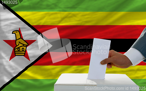 Image of man voting on elections in zimbabwe in front of flag