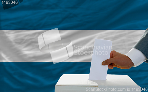 Image of man voting on elections in el salvador in front of flag