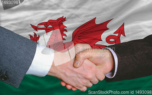 Image of businessmen handshake after good deal in front of wales flag