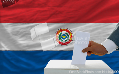 Image of man voting on elections in paraguay in front of flag