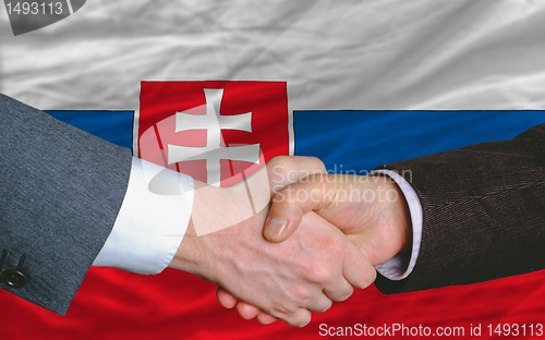 Image of businessmen handshake after good deal in front of slovakia flag