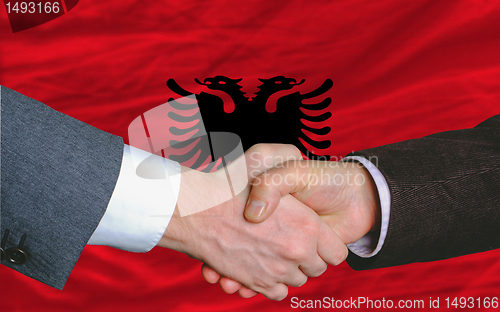 Image of businessmen handshake after good deal in front of albania flag