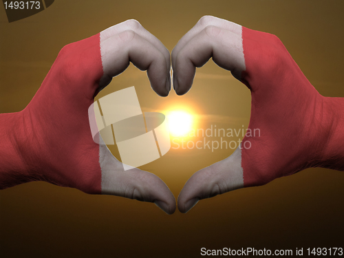 Image of Heart and love gesture by hands colored in peru flag during beau